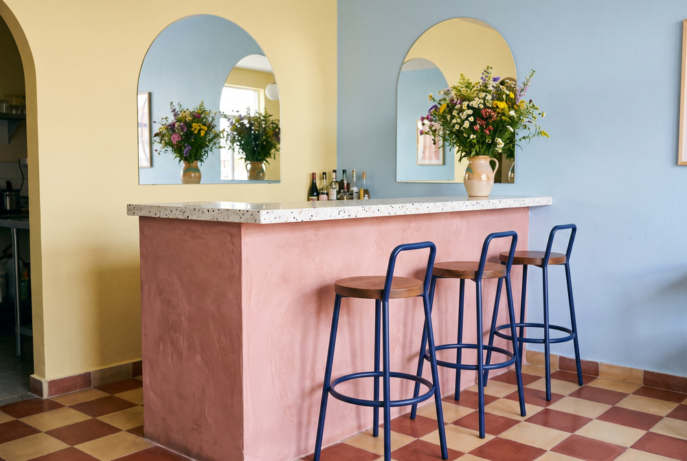 Barra rosa de terrazo en una cafetería con bancos redondos con respaldo en azul real