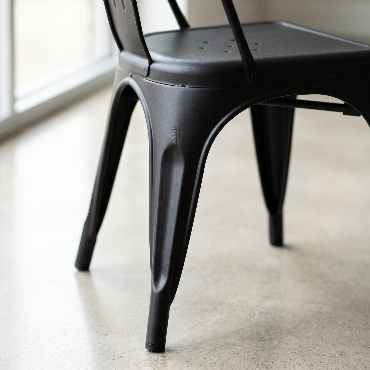 Detalle del asiento, la nervadura del respaldo y el taco antideslizante de la silla Tolix negra